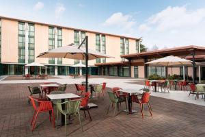 an outdoor patio with tables and chairs and umbrellas at Doubletree by Hilton Milan Malpensa Solbiate Olona in Solbiate Olona
