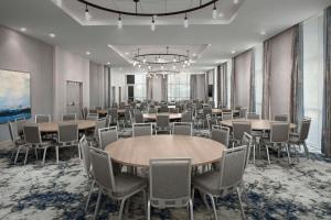 une salle de conférence avec des tables et des chaises ainsi qu'un lustre dans l'établissement Hilton Garden Inn Pensacola Downtown, à Pensacola