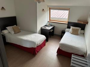 Cette chambre comprend deux lits, un bureau et une fenêtre. dans l'établissement Auberge Champenoise, à Moussy