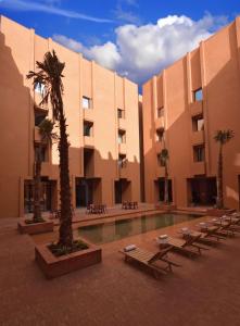 un edificio con un patio con piscina y palmeras en Doubletree By Hilton Ben Guerir Hotel & Residences, en Benguerir