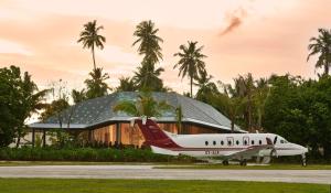 a plane parked on a runway in front of a building at Waldorf Astoria Seychelles Platte Island in Platte Island