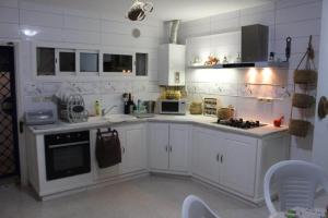 a white kitchen with white cabinets and appliances at Dar Sarra in Sousse