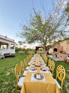 a long table with yellow table cloth and yellow chairs at 4-BRS Entire FarmHouse in Ismailia lGreen Paradise in Ismailia