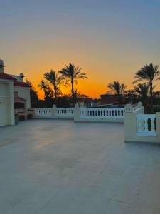 un tramonto dietro una recinzione bianca e palme di 4-BRS Entire FarmHouse in Ismailia lGreen Paradise a Ismailia