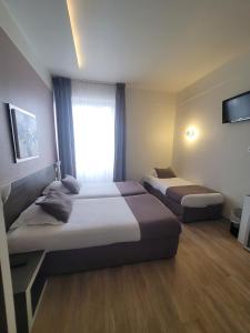 ein Hotelzimmer mit 2 Betten und einem Fenster in der Unterkunft HOTEL KYRIAD ORANGE Centre Ville - A7-A9 - 3 Etoiles - HOTEL DES PRINCES - Provence Alpes Côte d'Azur - France in Orange