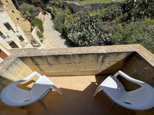 Duas cadeiras brancas sentadas em cima de uma varanda em The Nest Siekel Townhouse em Għajn il-Kbira