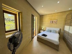 um quarto com uma cama, uma ventoinha e uma janela em The Nest Siekel Townhouse em Għajn il-Kbira