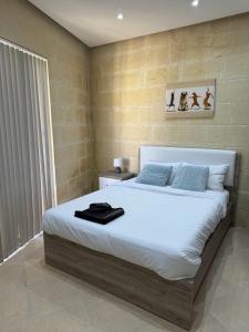 um quarto com uma cama grande com lençóis brancos e almofadas azuis em The Nest Siekel Townhouse em Għajn il-Kbira