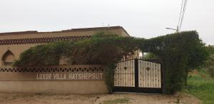 a gate in front of a building with a bush at Luxor Villa Hatshepsut in Luxor