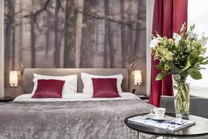 a bedroom with a bed and a table with a vase of flowers at The Queens Gate Hotel in London