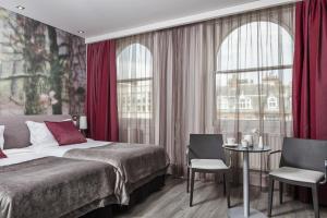 a bedroom with a bed with red curtains and a table at The Queens Gate Hotel in London