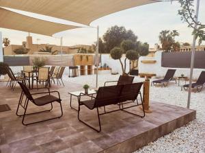un patio con sillas, mesas y una sombrilla en Chalet "El Paraíso del Cabo", en Retamar