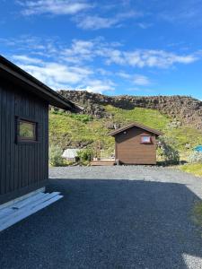 a barn and a building on a gravel road at Hlíðarás Guesthouse in Ölfus