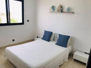 ein Schlafzimmer mit einem großen weißen Bett mit blauen Kissen in der Unterkunft My Cosy Place Rabat - Maison harhoura vue mer in Temara