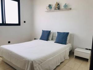 1 dormitorio con cama blanca y almohadas azules en My Cosy Place Rabat - Maison harhoura vue mer en Temara