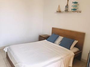 My Cosy Place Rabat - Maison harhoura vue mer في تمارة: غرفة نوم بسرير ذو شراشف بيضاء ومخدات زرقاء