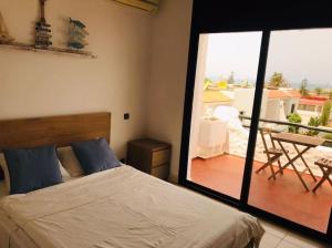 a bedroom with a bed and a view of a balcony at My Cosy Place Rabat - Maison harhoura vue mer in Temara