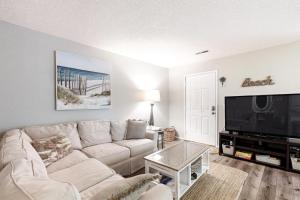 ein Wohnzimmer mit einem weißen Sofa und einem Flachbild-TV in der Unterkunft Waccamaw Condo - Unit 6 in Myrtle Beach