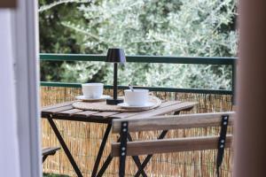 a wooden table with two cups and a lamp on a balcony at Casa Rosetta - Relax in Centro - Parcheggio Privato, Mare a 2 Passi in Bordighera