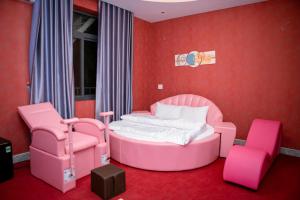 een roze slaapkamer met een bed en 2 stoelen bij Thành Phố Mới Hotel in Ðịnh Hòa