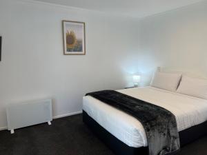 um quarto com uma cama e uma fotografia na parede em Magnolia Court Motel em Opotiki