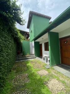 una casa verde y blanca con una puerta y un patio en Pousada Recanto das Tartarugas, en Maresias
