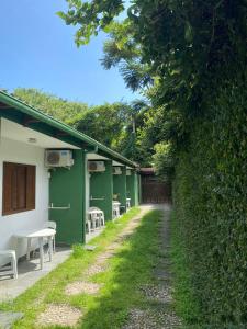 a row of green buildings with tables and chairs at Pousada Recanto das Tartarugas in Maresias