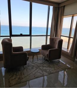 two chairs and a table in a room with a view of the ocean at اطلالة الحوراء in Umm Lujj