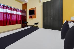 a bedroom with a bed and a tv and curtains at OYO Thulasi Residency in Srīrangam
