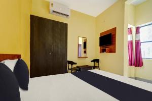 a bedroom with a bed and a door with a television at OYO Thulasi Residency in Srīrangam