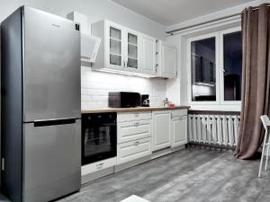 a kitchen with white cabinets and a stainless steel refrigerator at CLASSY APARTMENTS - Gdynia - Experyment in Gdynia