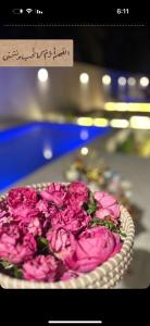 talerz różowych kwiatów na stole z znakiem w obiekcie شاليهات جزلا w mieście Al-Hufuf