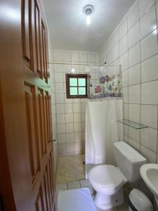 een witte badkamer met een toilet en een wastafel bij Pousada Recanto das Tartarugas in Maresias