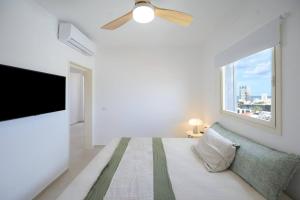 - une chambre blanche avec un lit et une télévision à écran plat dans l'établissement Mykonos Vibes - 3 BR, à Tel Aviv