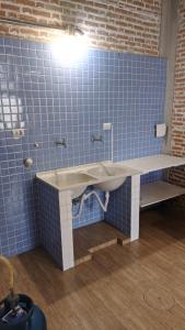 La salle de bains est pourvue d'un lavabo et d'un mur carrelé bleu. dans l'établissement Charmoso e confortável com A/C, à Pindamonhangaba