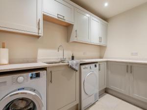 a kitchen with white cabinets and a washer and dryer at Nupton Hop Kiln in Kings Pyon