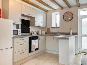 a kitchen with white cabinets and a clock on the wall at Jasmine Cottage in Elton