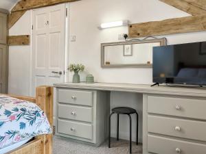 a bedroom with a desk with a tv and a bed at Jasmine Cottage in Elton