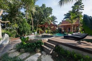 a backyard with a pool and a house at Berlima Wooden Lodge by Pramana Villas in Ubud