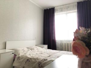 a bedroom with a bed and a window at Уютные апартаменты рядом с Ситицентром in Uralsk