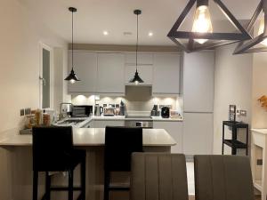 a kitchen with white cabinets and a island with chairs at London Southgate 2bed Apartment in London
