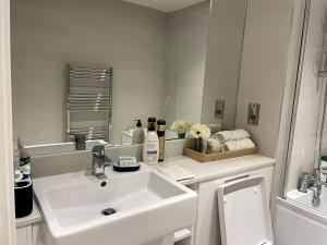 a white bathroom with a sink and a mirror at London Southgate 2bed Apartment in London