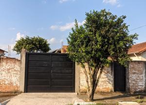 una puerta de garaje negra con un árbol delante en Charmoso e confortável com A/C, en Pindamonhangaba