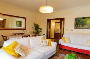 una sala de estar con sofás blancos y almohadas amarillas. en Villa Taala con terraza, en Los Nietos