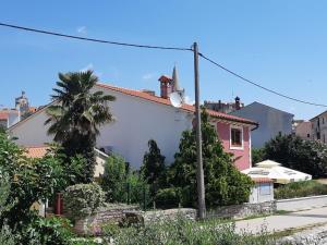 ein weißes Gebäude mit einer Palme neben einer Straße in der Unterkunft Ferienwohnung mit Terrasse für sechs Personen in Bale