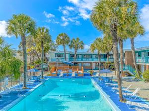 une piscine bordée de palmiers et de chaises ainsi qu'un bâtiment dans l'établissement Sun Fun, à Myrtle Beach