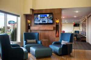レッドディアにあるTownePlace Suites by Marriott Red Deerの青い椅子と薄型テレビ付きの待合室