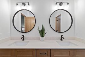 two sinks in a bathroom with two mirrors at Dells Domain 2.0 in Wisconsin Dells