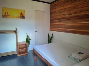 a bedroom with a white bed and a wooden wall at NoBi's Inn, Port Barton in San Vicente