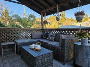 eine Terrasse mit Korbmöbeln und einem Tisch in der Unterkunft Beautiful Spacious Victorian Garden Oasis Central, Gated, Deck, BBQ in San Rafael